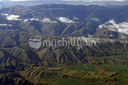 Aerial view showing the contours of  hills and mountains in Central Otago with a green irrigated valley of farmland.