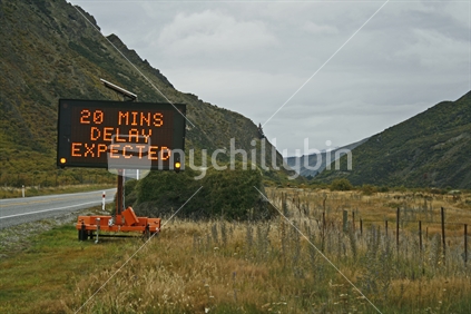 TSign warning of traffic delays, while Nevis Bluff is blasted to remove loose rocks for safety.  Central Otago.