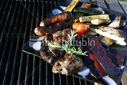 Fresh tomatoes and rosemary to garnish a platter of chargrilled barbeque meat and vegetables.