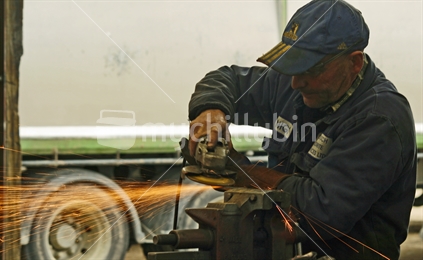 A tradesman, grinding a metal plate in an engineering workshop.