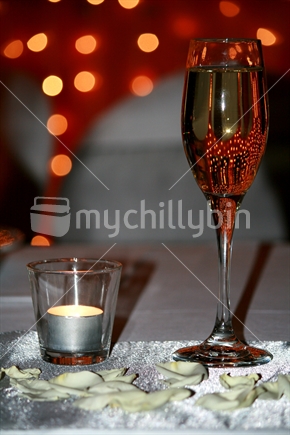 A single glass of champagne on the bridal table, with lights reflected