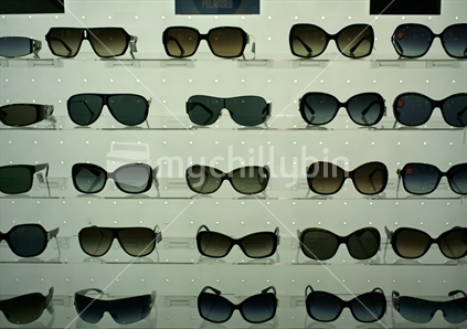 Sunglasses displayed on shelves in a shop.