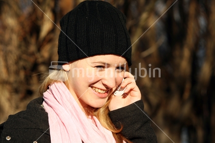 A young new Zealand woman, talking on a cellphone.