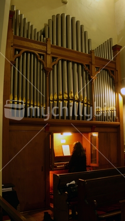 A person practicing at a large pipe organ in a church.