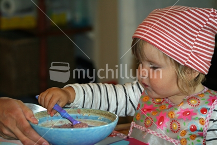 A young girl concentrating on loading her spoon.