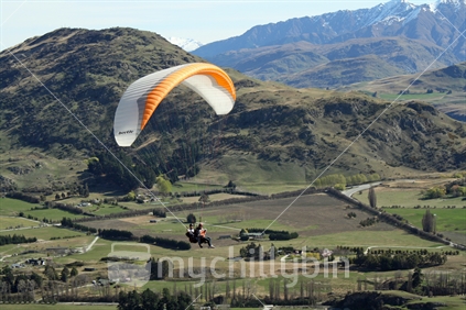 Paragliding over hills and farmland in Central Otago.