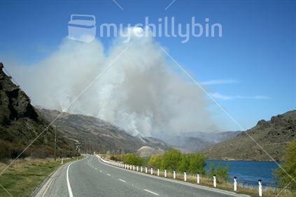Main highway between Cromwel and Alexandra with smoke cloud from a controlled burnoff.