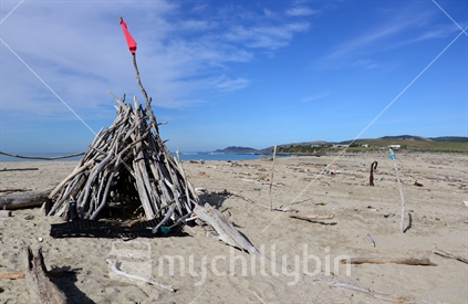 A driftwood tepee with Nugget and Kaka Points in the distance.