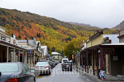 The main street of Arrowtown, with vehicles parked along curbside.