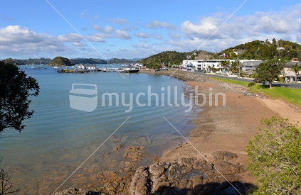 Paihia beach with Paihia wharf and waterfront in the distance.  A popular tourist destination in the Bay of Islands.