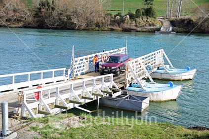 Tuapeka Mouth Ferry, moored tied at landing jetty, unloading vehicles after crossing the Clutha River.