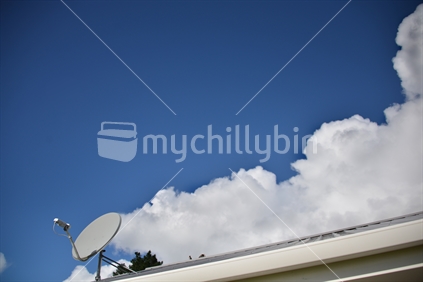 A digital dish with blue sky and puffy white cumulus cloud.