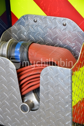 A coiled fire hose nestled in storage box. 