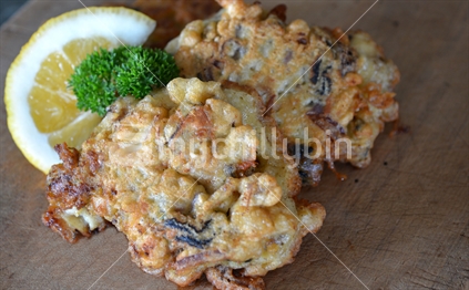 Crispy mussel fritters with lemon and parsley garnish.