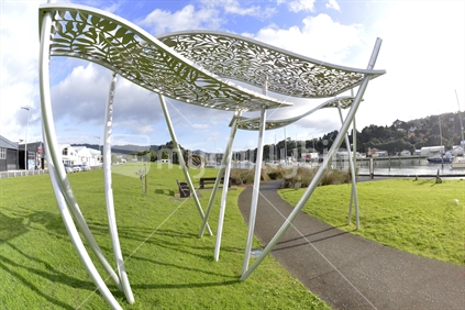 A silver metal sculpture, spanning across the footpath in Central Park, Whangarei.