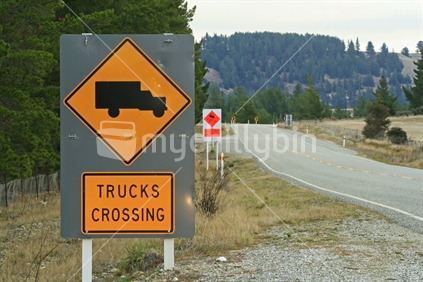 Trucks crossing and slippery. Signs on roadside.
