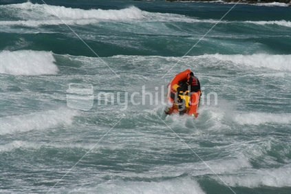 People in an inflatable boat, riding very rough waves.