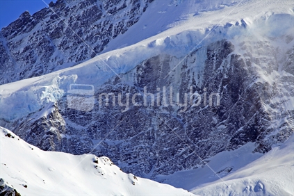 A thick blue ice glacial shelf with small avalanches and snowdrift.