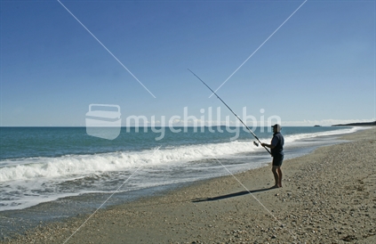A man surfcasting on a West Coast beach, South Island.