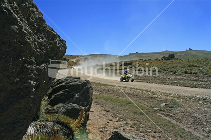 An exhilirating ride along a high country dusty dirt track on a quad bike. (focus foreground).