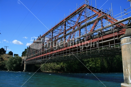 A metal bridge over the Clutha River surrounded by scaffolding for repair and painting.