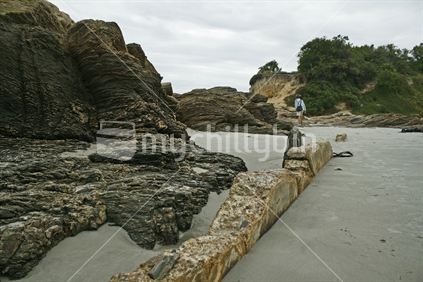 A structural wall, surrounded by sand and rocks, Brighton beach, East Coast, South Island,