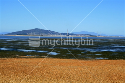Low tide in a tidal estuary with Tiwai Point and Bluff hill in the distance.