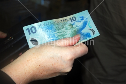 Woman pays with a New Zealand 10 dollar note.