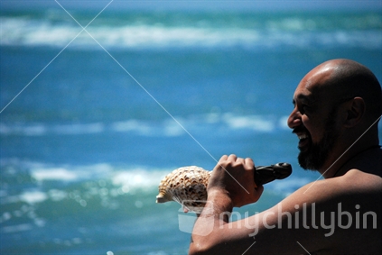 Man playing putatara at the beach