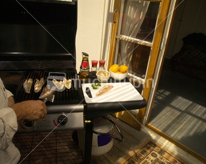 Image of a barbeque with hand turning frying fish