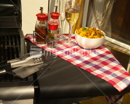 Image of a barbeque with tongs and salad in bowl