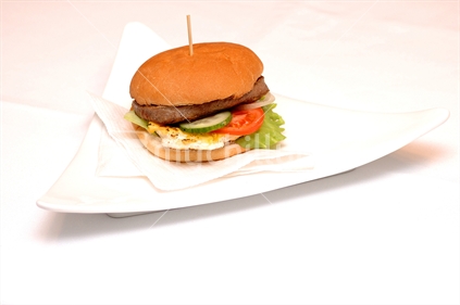 Image of egg burger on a white plate with pink back ground