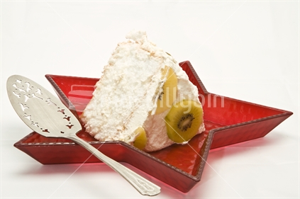 Image of Pavlova pudding, slice on red star shaped tray with antique silver spatula