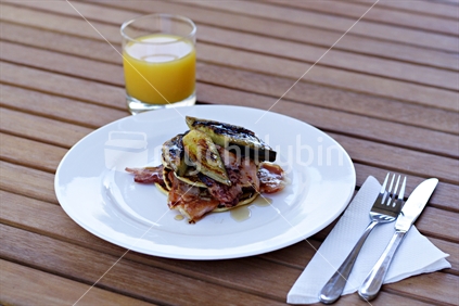 Breakfast setting outside on the picnic table, with napkin, knife and fork, plus a glass of OJ 