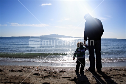 Father Holding Son's hand, Silhouetted against Rangitoto Island, Mission Bay, Auckland. Landscape