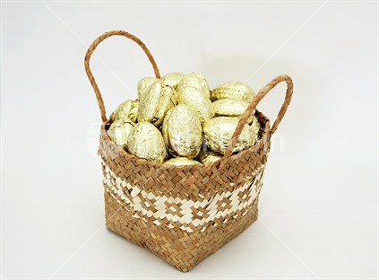 Golden wrapped Easter marshmellow eggs in flax Basket
