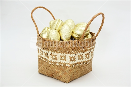 Golden wrapped Easter marshmellow eggs in flax Basket