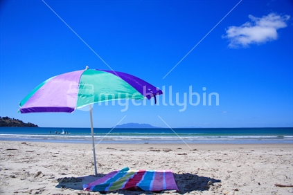 Beach umbrella and towel on Omaha Beach, New Zealand