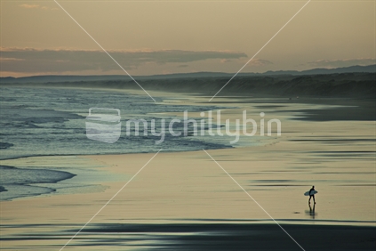 A lone surfer on Muriwai beach, North Island, New Zealand