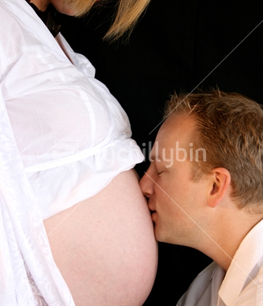 Father kissing pregnant tummy