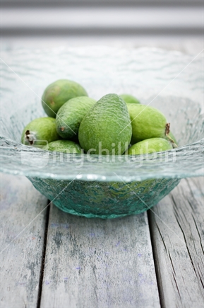 Feijoas in glass fruit bowl on wooden table