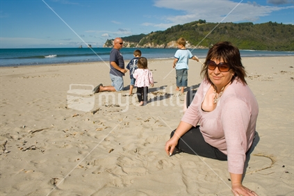Mother looking with children and father playing in background