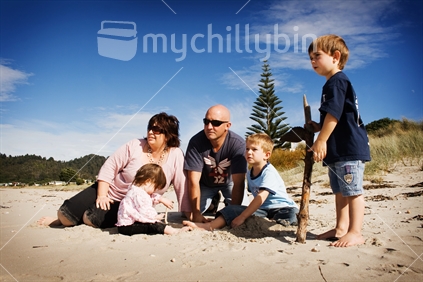 Family of five sitting on beach looking out to sea