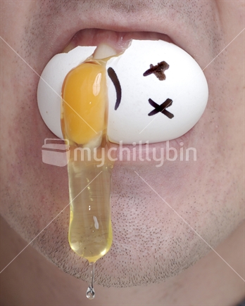 A man bites into a chicken egg, yolk oozes out