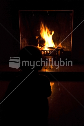 A silhouette of a child in front of a fireplace