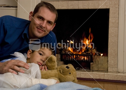 A man and and injured boy relax near a lounge fire
