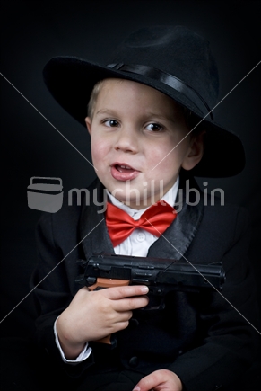 Boy holds a toy gun dressed as a 1930's gangster