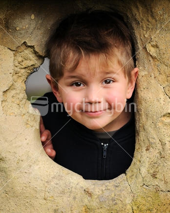 A boy peers through a clay window