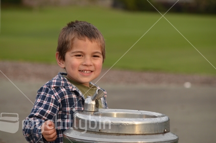 A smiling boy in front of a water fountain