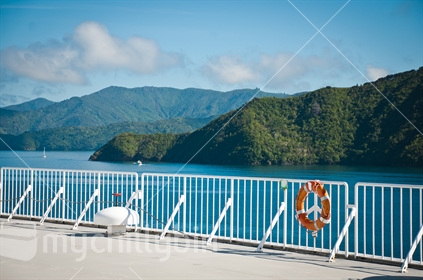 The deck and railing of an inter-island ferry as it passes through the Marlborough Sounds